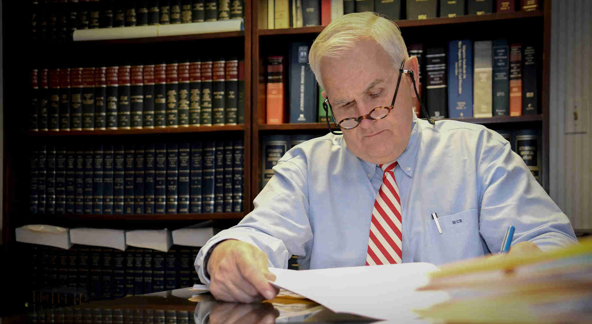 Image of William C. Brewer of Brewer & Giggenbach sitting at his desk reviewing a case from a new client.